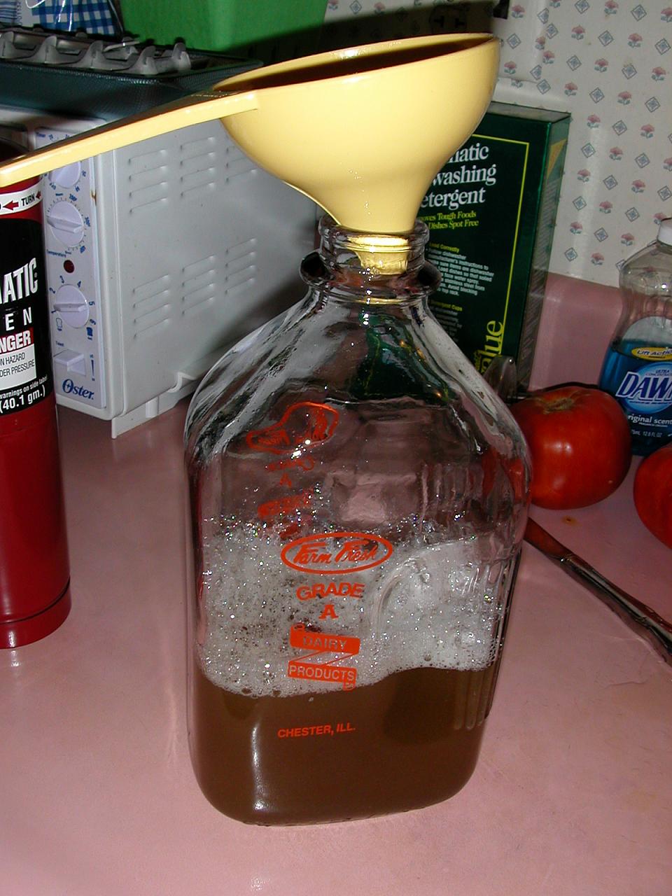Using the sanitized funnel, add the cooled wort and yeast to the container.